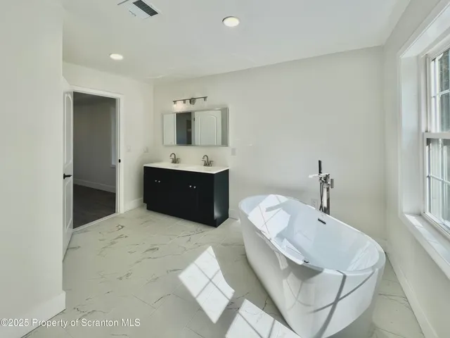 a spacious bathroom with a tub sink and mirror