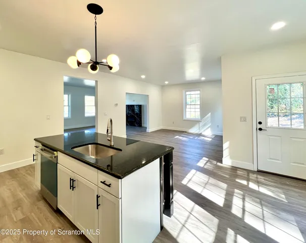a kitchen with stainless steel appliances granite countertop a sink a counter space and wooden floor