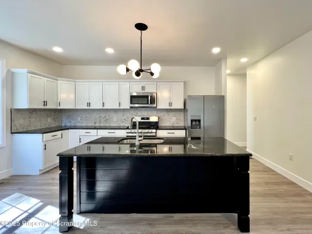 a kitchen with stainless steel appliances granite countertop a sink a stove and cabinets