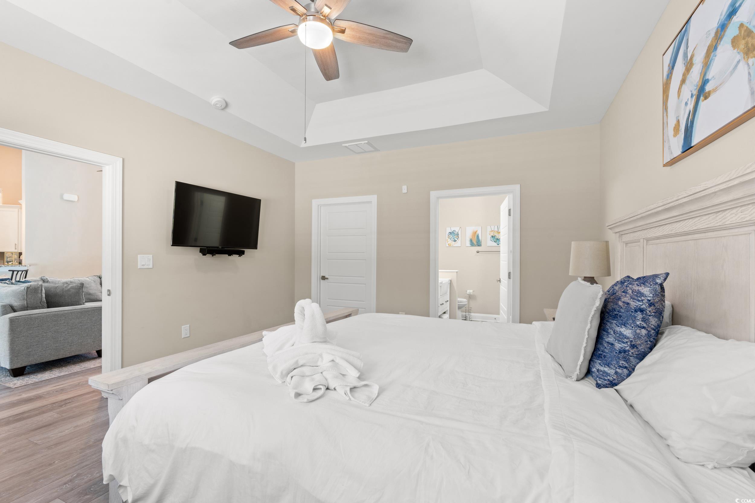 714 Charlotte Road Myrtle Beach, SC 29577 - Photo 15 of 30 Bedroom featuring a raised ceiling, ensuite bathroom, wood finished floors, and ceiling fan