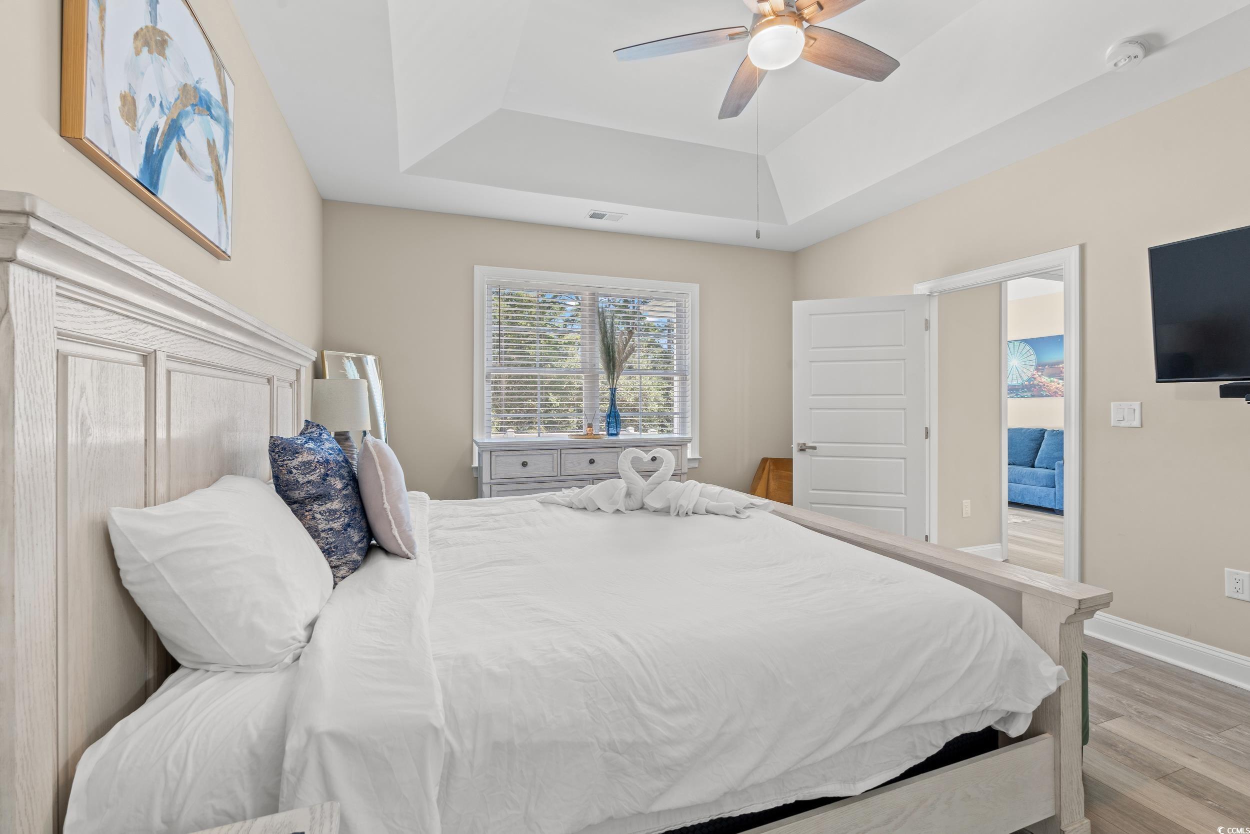 714 Charlotte Road Myrtle Beach, SC 29577 - Photo 16 of 30 Bedroom with a tray ceiling, light wood-type flooring, and a ceiling fan