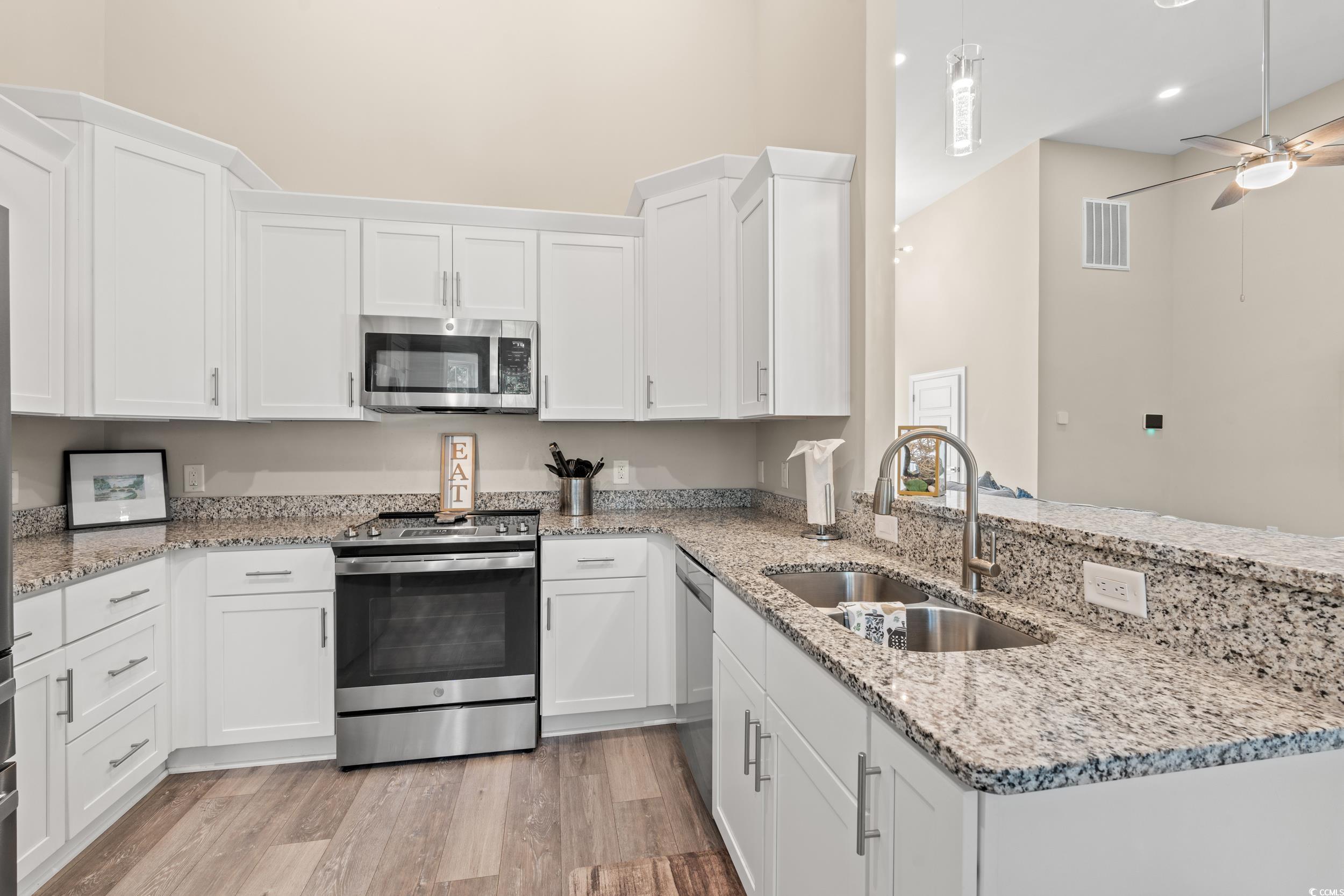 714 Charlotte Road Myrtle Beach, SC 29577 - Photo 10 of 30 Kitchen with stainless steel appliances, light stone countertops, white cabinets, light wood-type flooring, and a towering ceiling