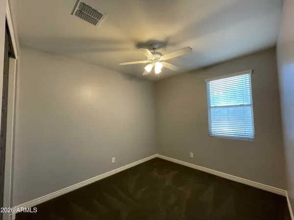 an empty room with a ceiling fan and closet area
