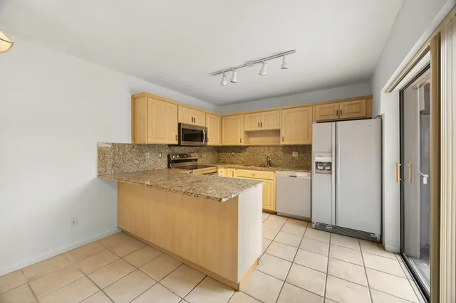 a kitchen with stainless steel appliances granite countertop a refrigerator and a stove top oven