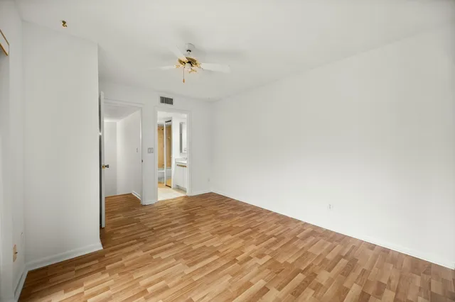 a view of empty room with wooden floor and fan