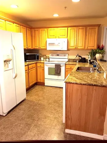 a kitchen with stainless steel appliances granite countertop a stove a sink and a refrigerator with wooden cabinets
