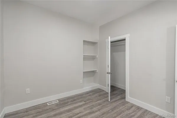a view of an empty room with wooden floor and closet