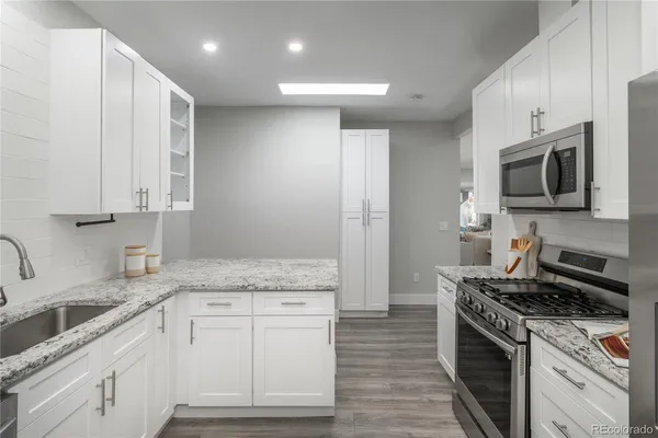 a kitchen with granite countertop a sink stainless steel appliances and cabinets