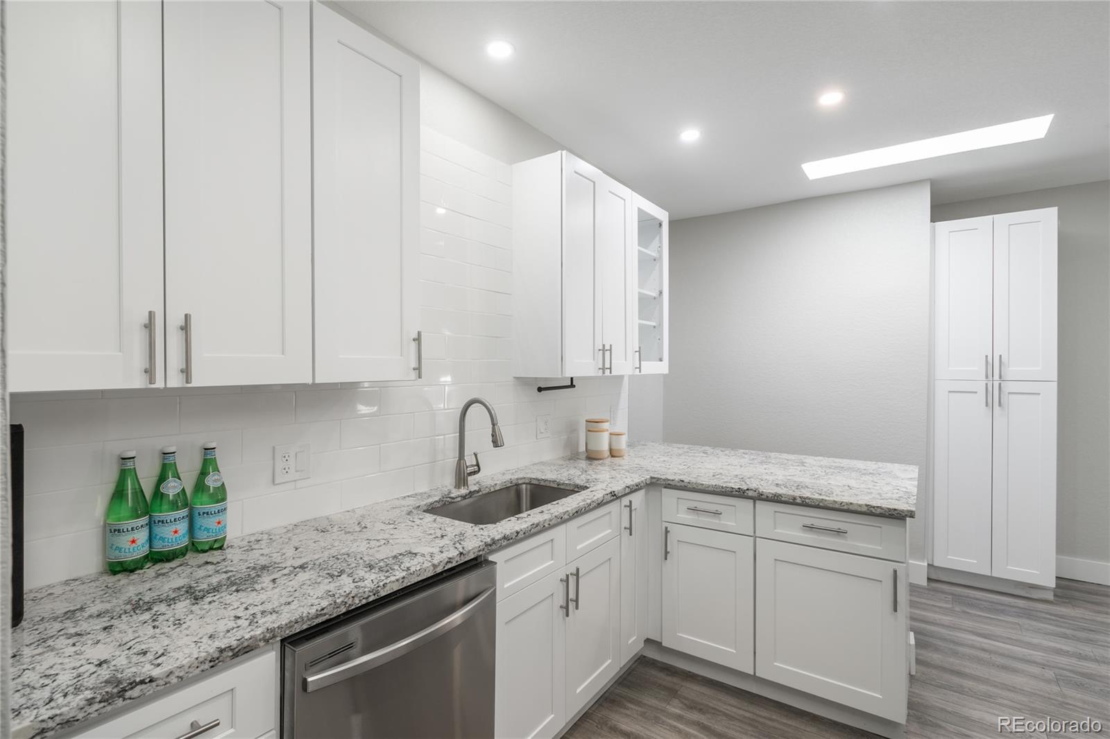 2339 South Acoma Street Denver, CO 80223 - Photo 17 of 36 a kitchen with a sink dishwasher and white cabinets with wooden floor