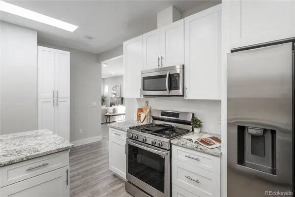 a kitchen with granite countertop cabinets stainless steel appliances and wooden floor