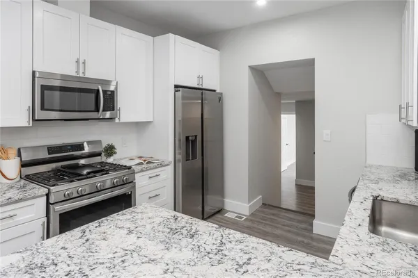 a kitchen with stainless steel appliances kitchen island granite countertop a refrigerator stove and sink