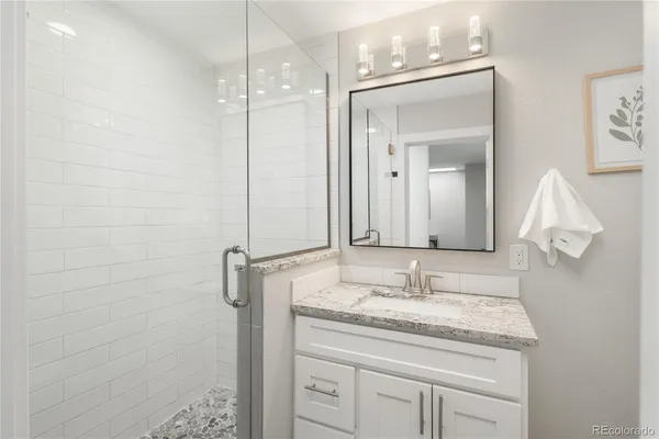 a bathroom with a granite countertop sink a mirror and shower