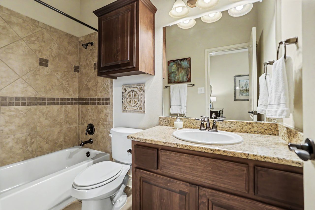 809 Prairie Dunes Drive Georgetown, TX 78628 - Photo 21 of 40 A well-appointed bathroom with a classic tub-shower combo and a vanity featuring a granite countertop.