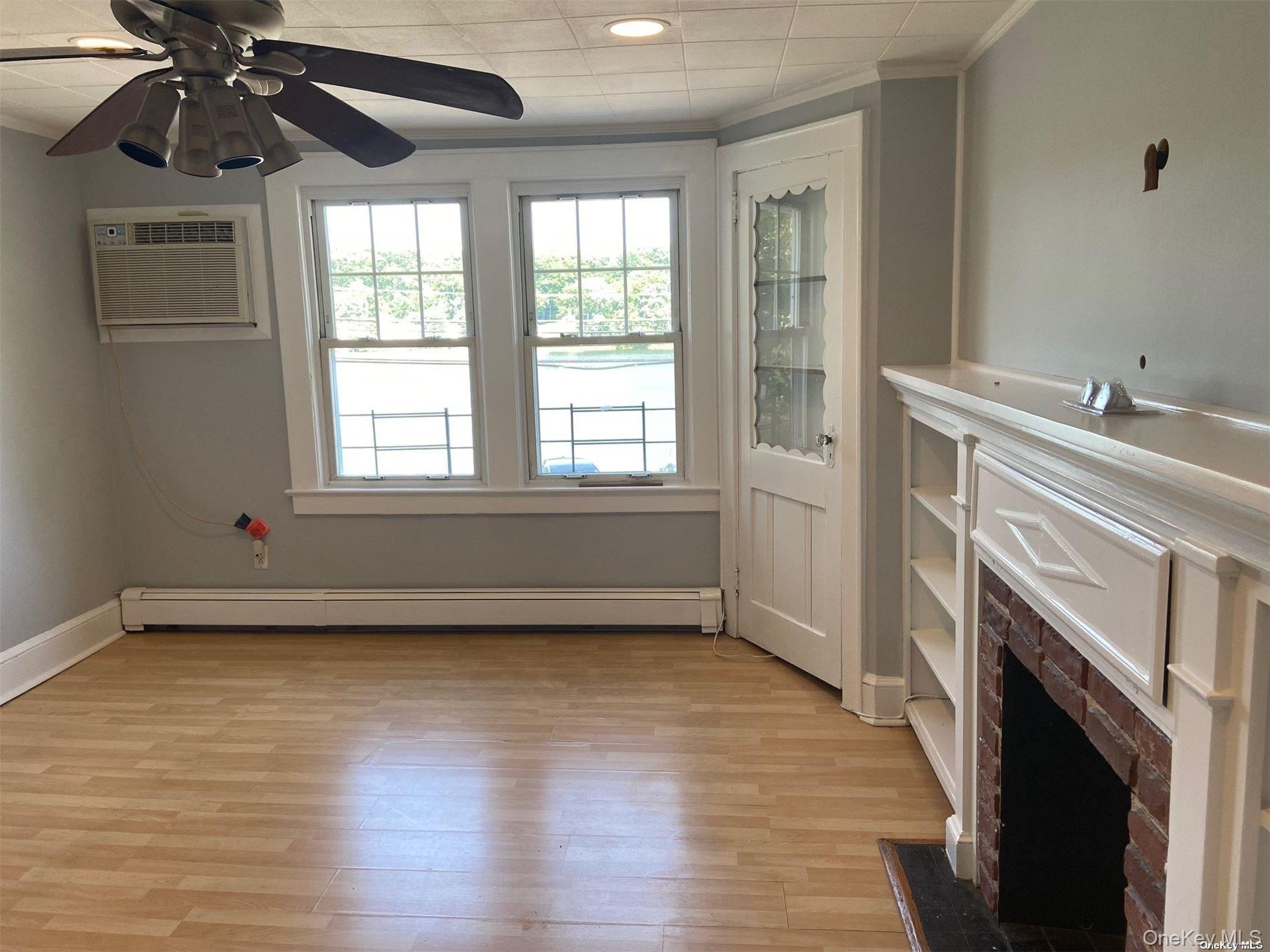 51 Centershore Road, Unit UPPR Centerport, NY 11721 - Photo 11 of 20 an empty room with windows fireplace and wooden floor