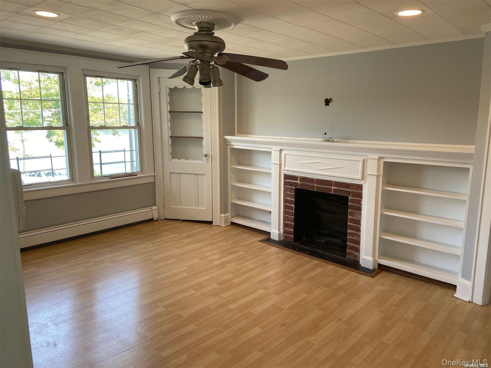 51 Centershore Road, Unit UPPR Centerport, NY 11721 - Photo 10 of 20 an empty room with a fireplace cabinet and windows