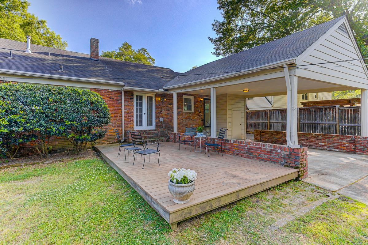 5676 Barfield Road Memphis, TN 38120 - Photo 3 of 19 Rear exterior featuring an elevated wood deck, brick facade, a covered carport, and a mature shrub