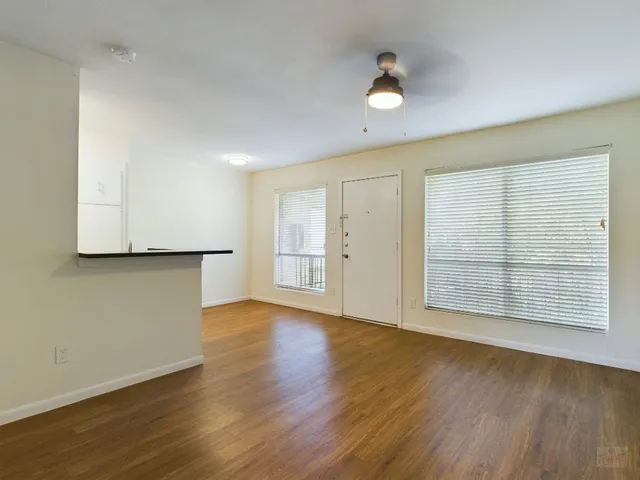an empty room with wooden floor and windows