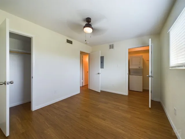 an empty room with wooden floor and windows
