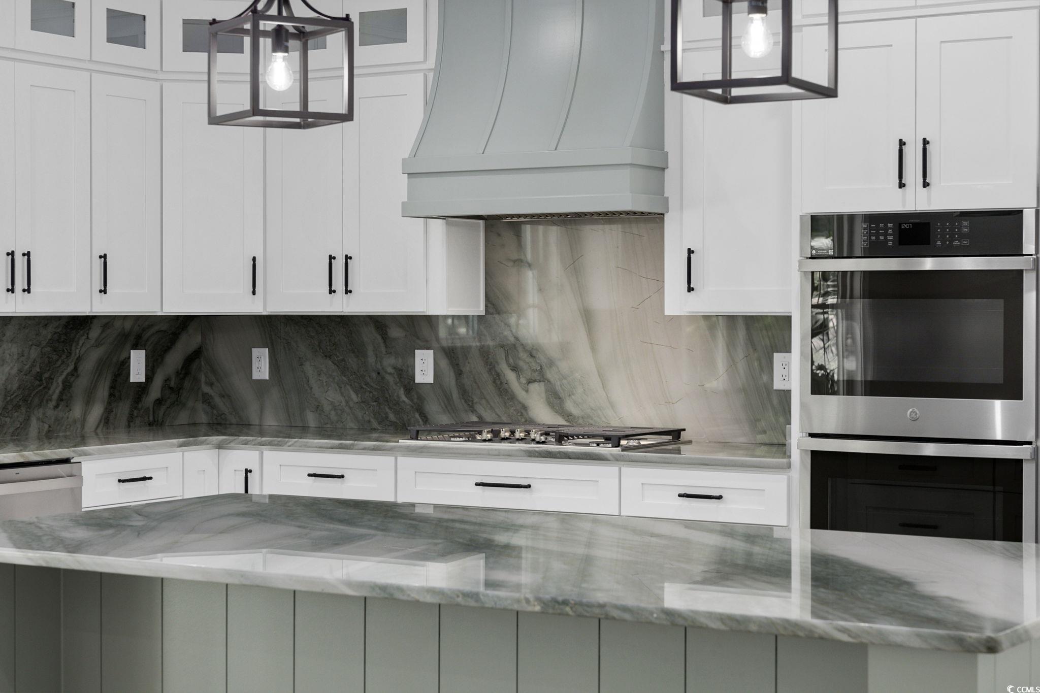 4806 North Kings Highway Myrtle Beach, SC 29577 - Photo 20 of 38 Kitchen with stainless steel double oven, premium range hood, glass insert cabinets, and white cabinets