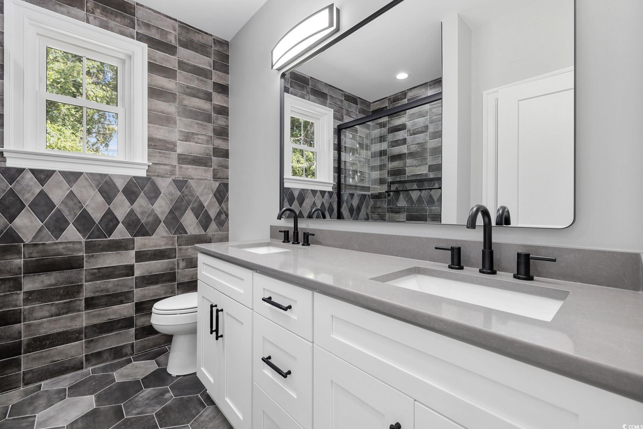 4806 North Kings Highway Myrtle Beach, SC 29577 - Photo 25 of 38 Full bath with tile walls, double vanity, tile patterned flooring, and a stall shower