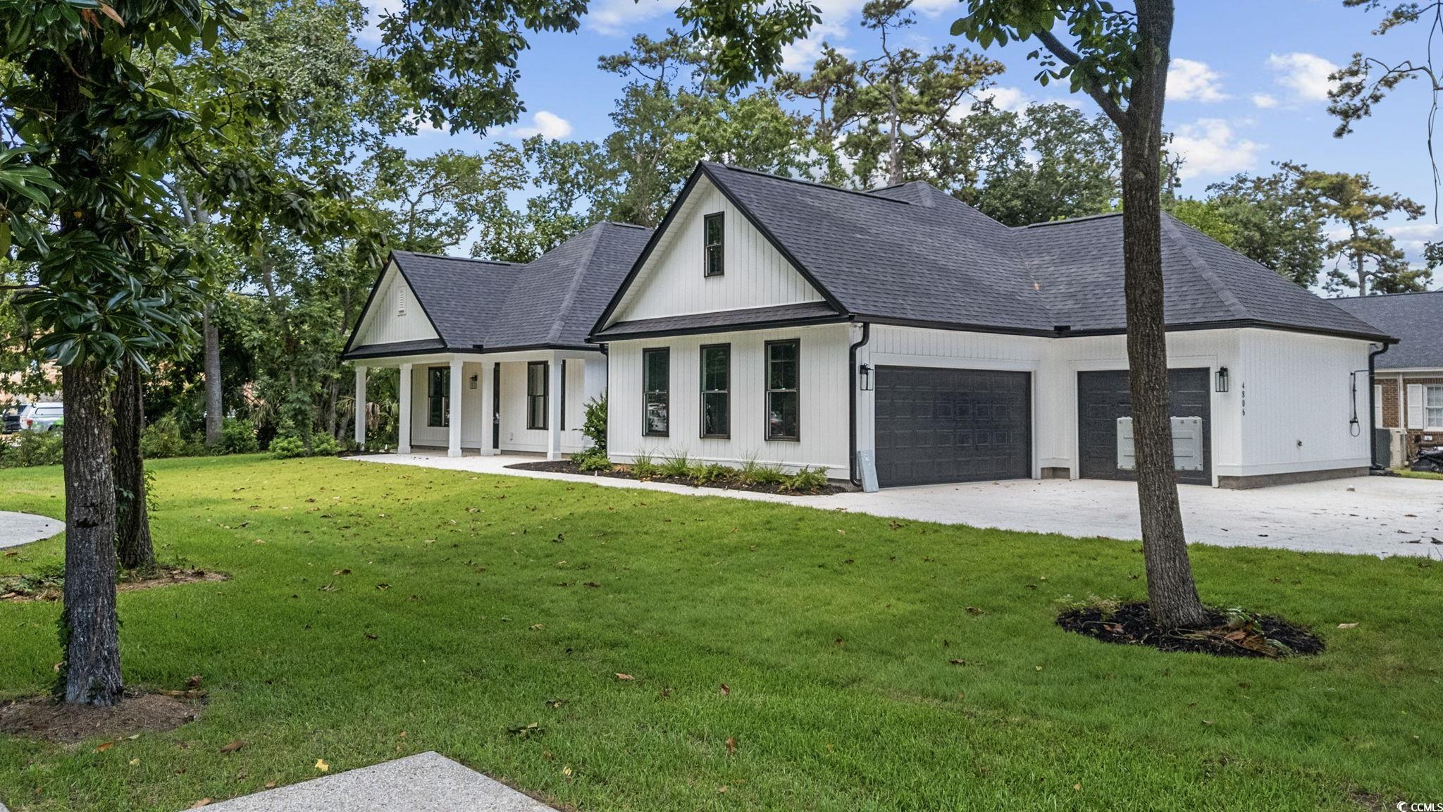 4806 North Kings Highway Myrtle Beach, SC 29577 - Photo 3 of 38 Modern farmhouse featuring an attached garage, concrete driveway, roof with shingles, and a front yard