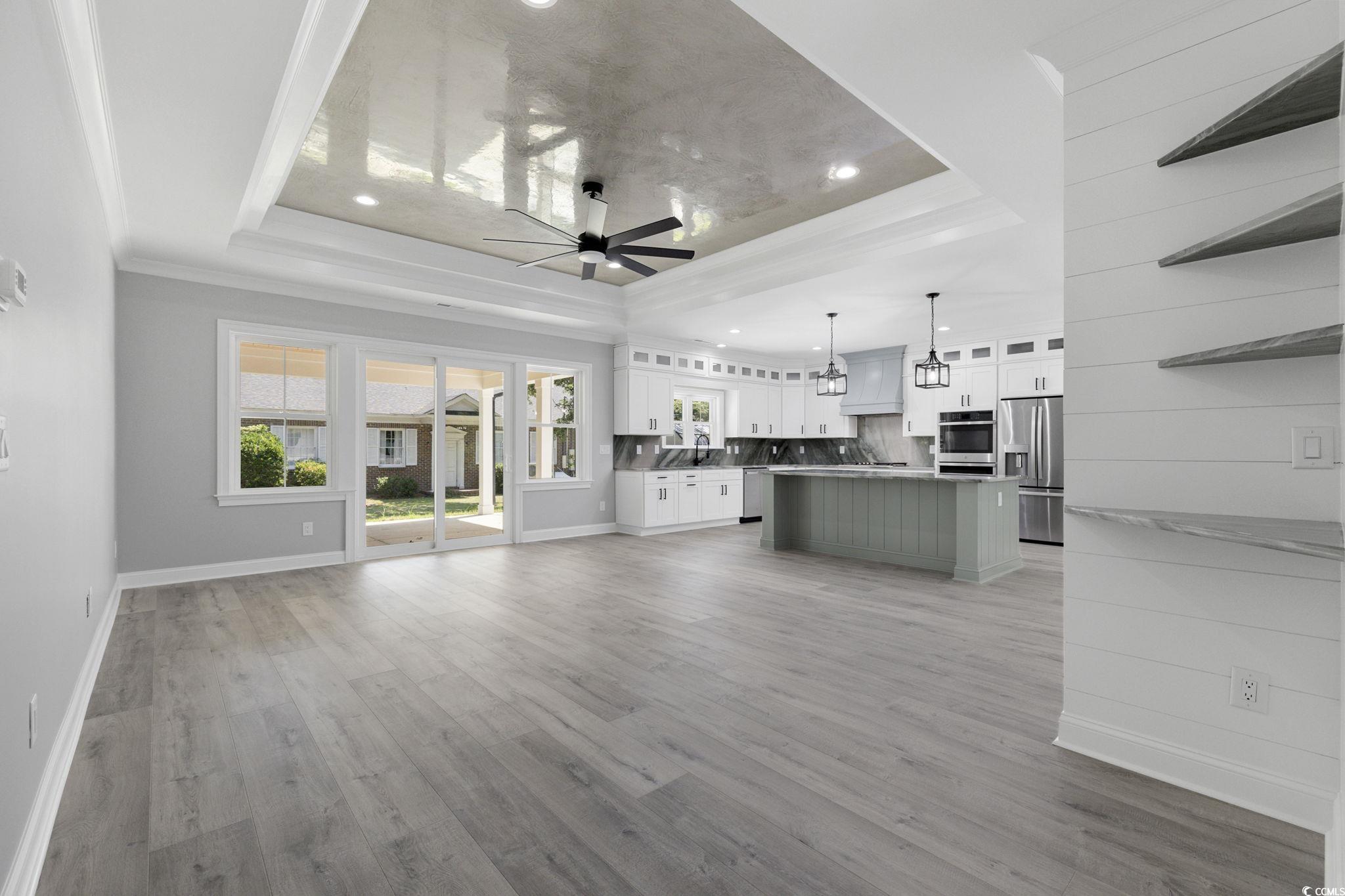 4806 North Kings Highway Myrtle Beach, SC 29577 - Photo 5 of 38 Unfurnished living room with ornamental molding, a ceiling fan, a tray ceiling, light wood-type flooring, and recessed lighting