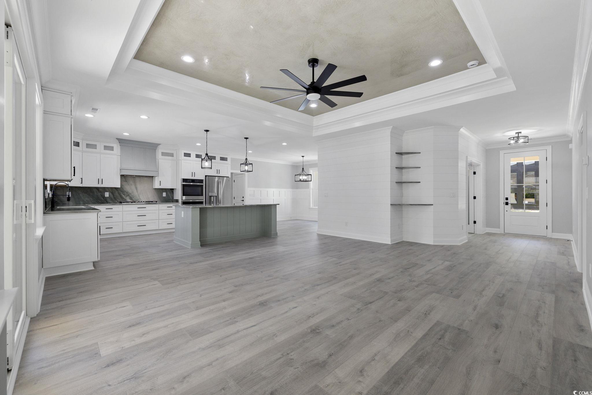 4806 North Kings Highway Myrtle Beach, SC 29577 - Photo 6 of 38 Unfurnished living room featuring a ceiling fan, crown molding, a tray ceiling, light wood finished floors, and recessed lighting