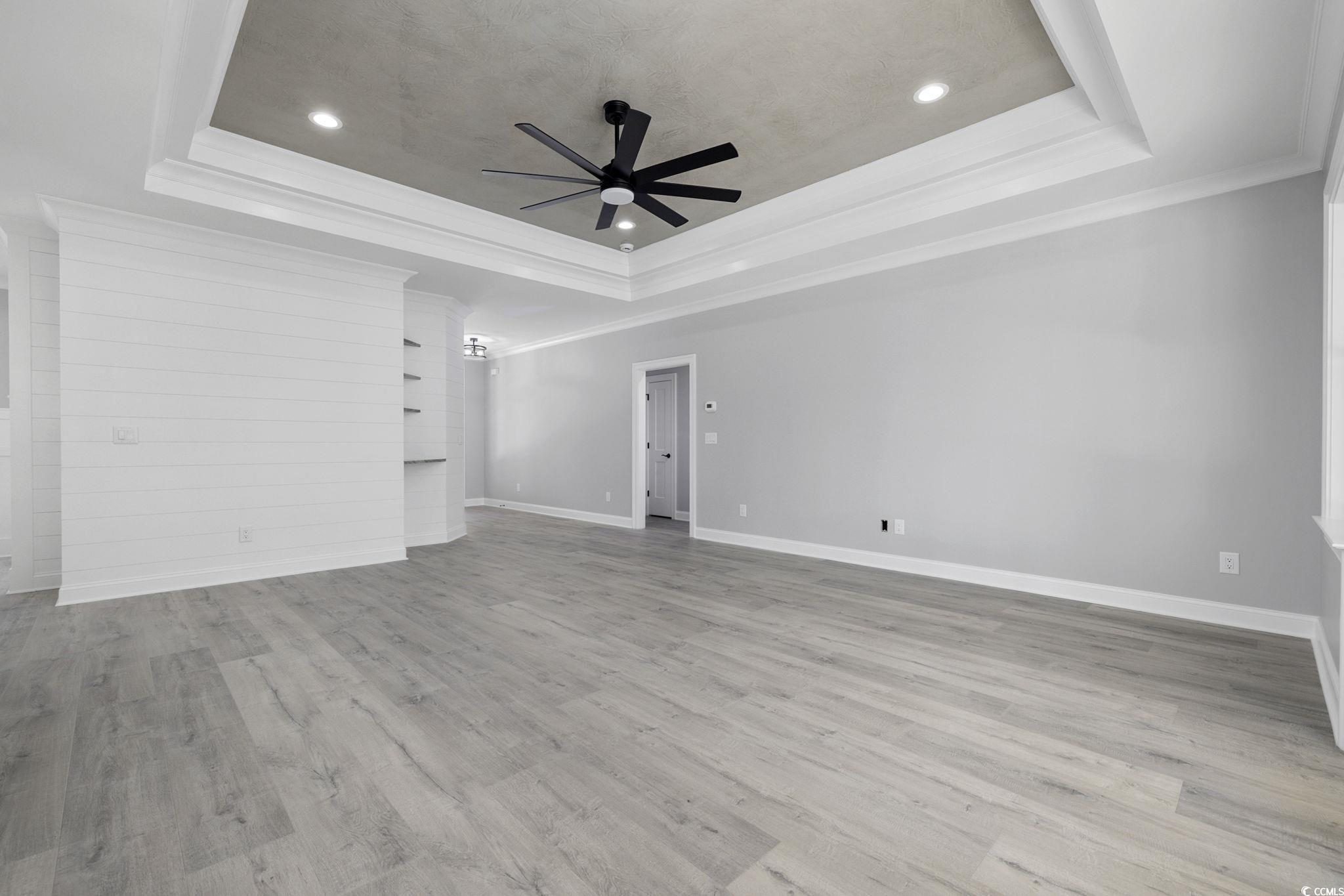 4806 North Kings Highway Myrtle Beach, SC 29577 - Photo 7 of 38 Unfurnished living room featuring ceiling fan, ornamental molding, wood finished floors, recessed lighting, and a tray ceiling