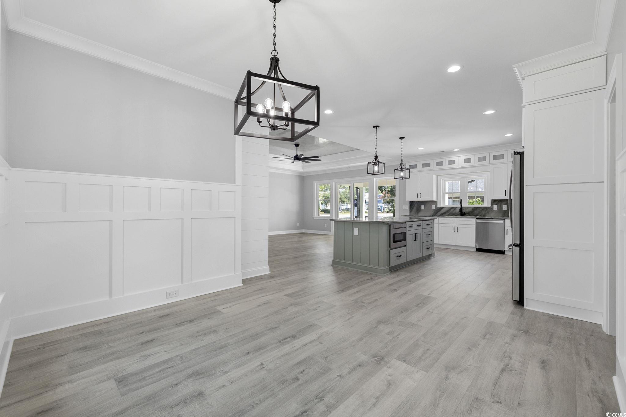 4806 North Kings Highway Myrtle Beach, SC 29577 - Photo 38 of 38 Kitchen with ornamental molding, open floor plan, a decorative wall, white cabinets, and a kitchen island