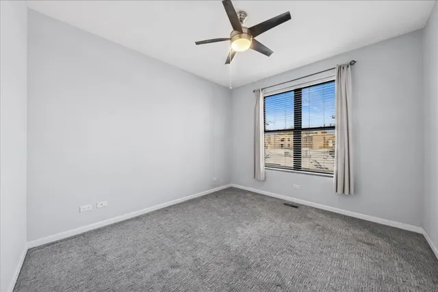 an empty room with a window and ceiling fan