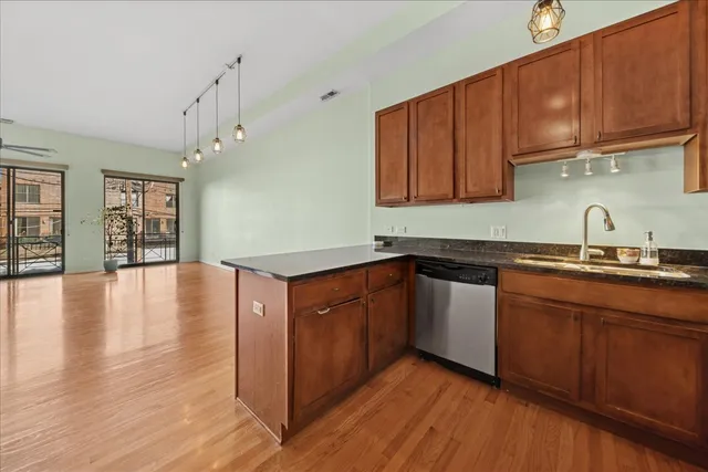 a kitchen with stainless steel appliances granite countertop wooden cabinets a sink and dishwasher with wooden floor