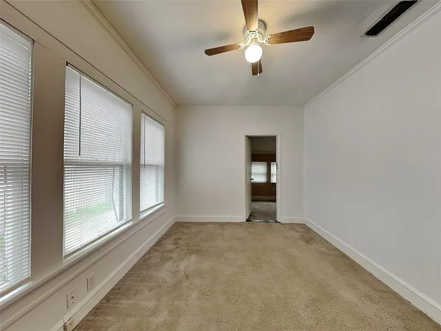 an empty room with chandelier fan and windows