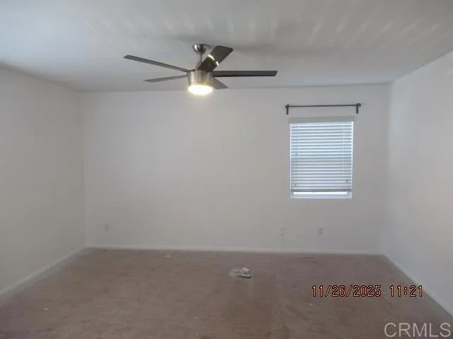 an empty room with a window and a fan