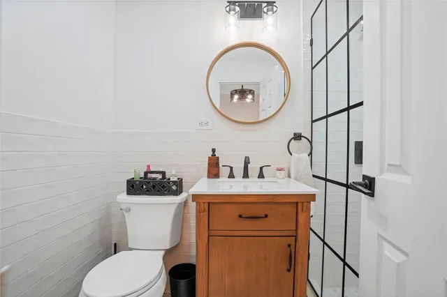 a bathroom with a toilet sink vanity and mirror