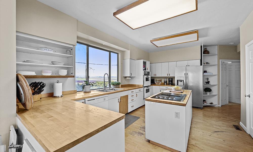 547 Mission Vineyard Road Hollister, CA 95023 - Photo 4 of 13 a kitchen with stainless steel appliances granite countertop a stove top oven a sink a refrigerator and white cabinets with wooden floor