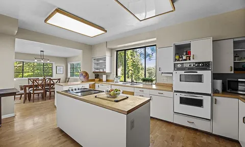 a kitchen with a stove cabinets and living room view