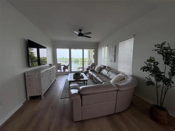 a living room with furniture a chandelier a large window with wooden floor