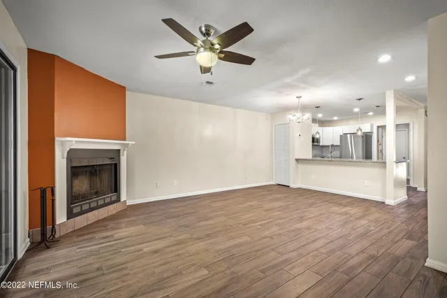 an empty room with wooden floor a fireplace and a kitchen space