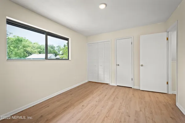 an empty room with wooden floor chandelier fan and windows