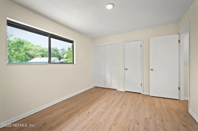 an empty room with wooden floor chandelier fan and windows