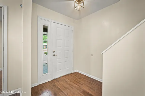 an empty room with wooden floor closet and windows