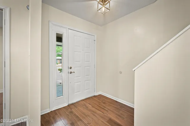an empty room with wooden floor closet and windows