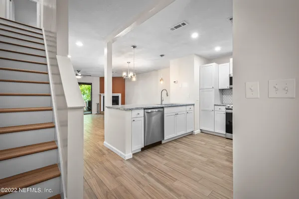 a kitchen with white cabinets and wooden floor