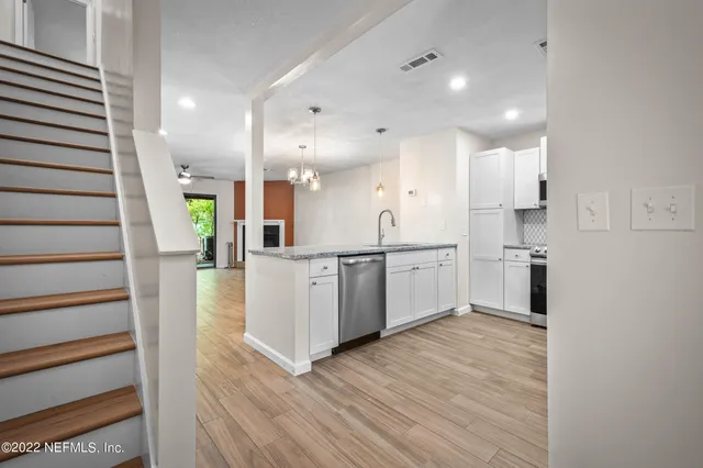a kitchen with white cabinets and wooden floor