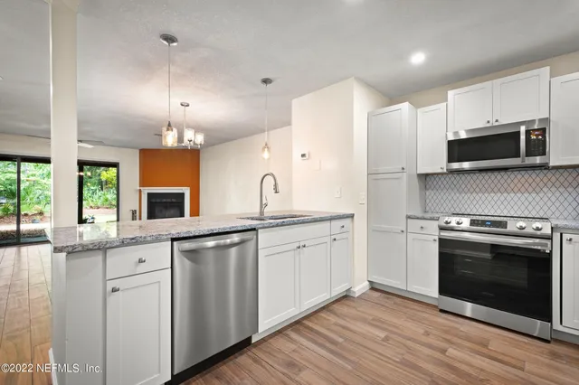 a kitchen with stainless steel appliances granite countertop a stove a sink and a microwave