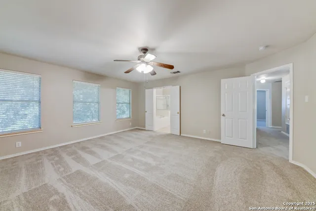 an empty room with windows and fan