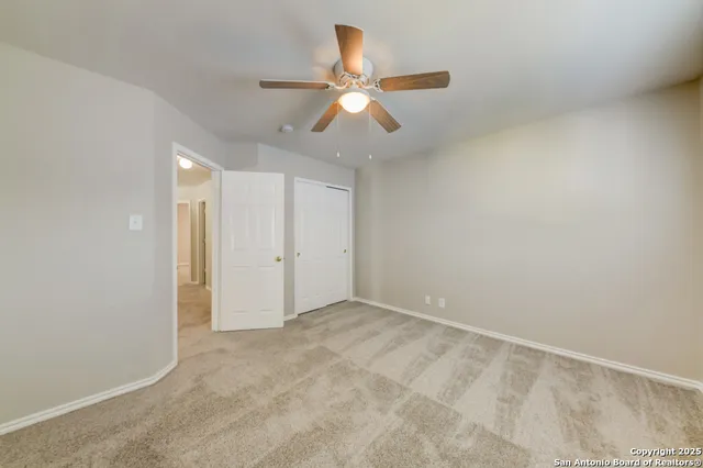 an empty room with closet and a chandelier fan
