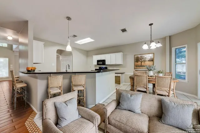 a living room with furniture a kitchen and a chandelier