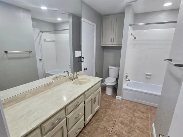a bathroom with a granite countertop sink a toilet and shower