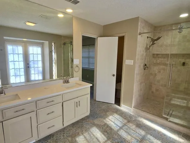 a spacious bathroom with a shower sink and mirror